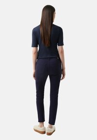 Námořnický krátký rukáv top, kombinovaný s úzkými námořnickými kalhotami a béžovými huňatými pantoflemi, které ukazují hladkou strukturu a přiléhavý design.