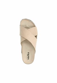 Beige cross-strap sandal with a soft suede texture, open toe, flat sole, and branding "sacha" embossed on the insole.