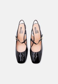 Μαύρα γυαλιστερά δερμάτινα πέδιλα με λουράκι πίσω, τετράγωνα δάχτυλα και λεπτές τιράντες, με την επωνυμία «Love Moschino» στις μπεζ σόλες, πάνω σε λευκό φόντο.