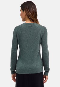 Maglione verde realizzato in materiale morbido con scollatura rotonda, polsini e orlo a costine. Texture liscia con minimalismo nei dettagli.