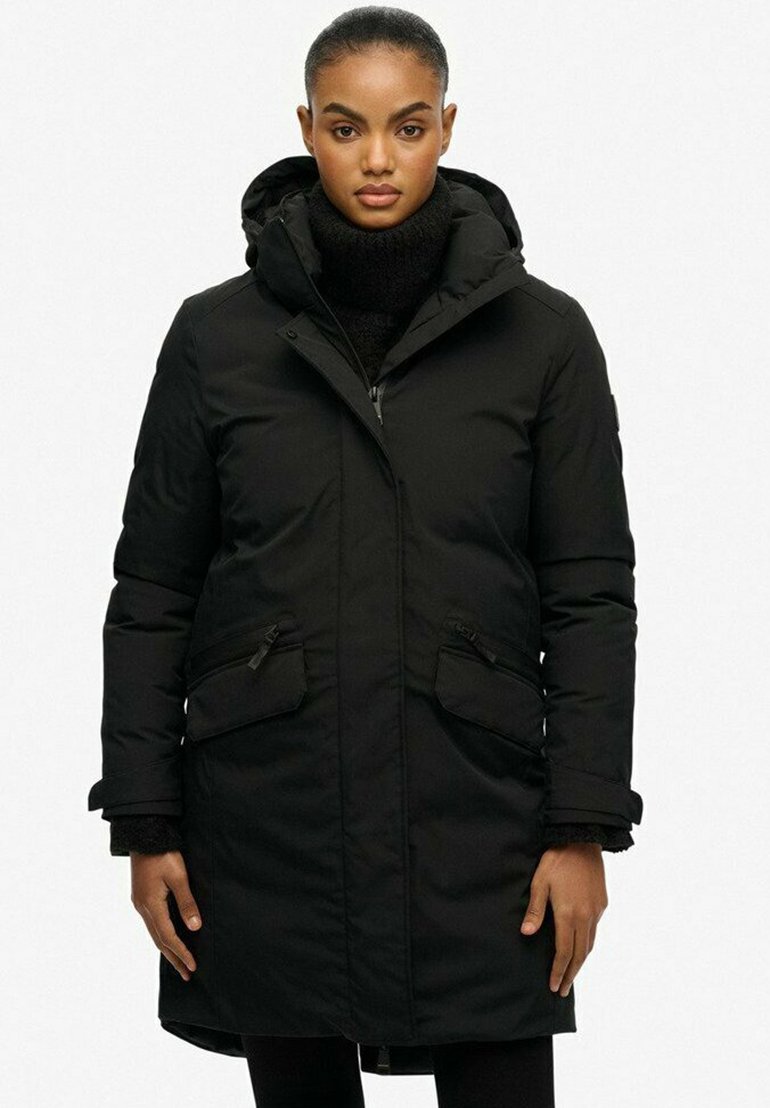 Czarna parka z kapturem, zapinana na zamek, z bocznymi kieszeniami i ściągaczami na mankietach. Charakteryzuje się gładką teksturą i średnią długością.