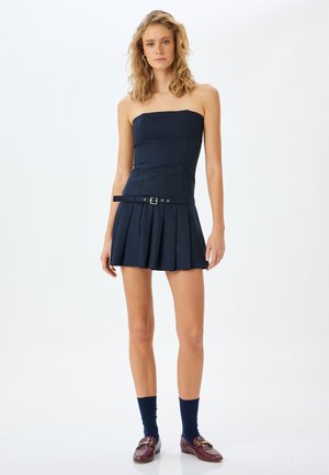 Vestido sin tirantes de color marino con un cuerpo ajustado y una falda plisada. Presenta una cintura ceñida con cinturón y una textura suave y estructurada.