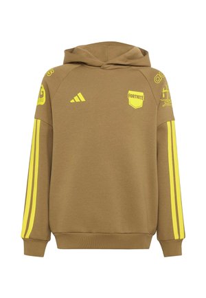 Ragazzo adolescente che indossa una felpa con cappuccio marrone e pantaloni con strisce gialle e logo Fortnite, in piedi davanti a uno sfondo chiaro e uniforme.