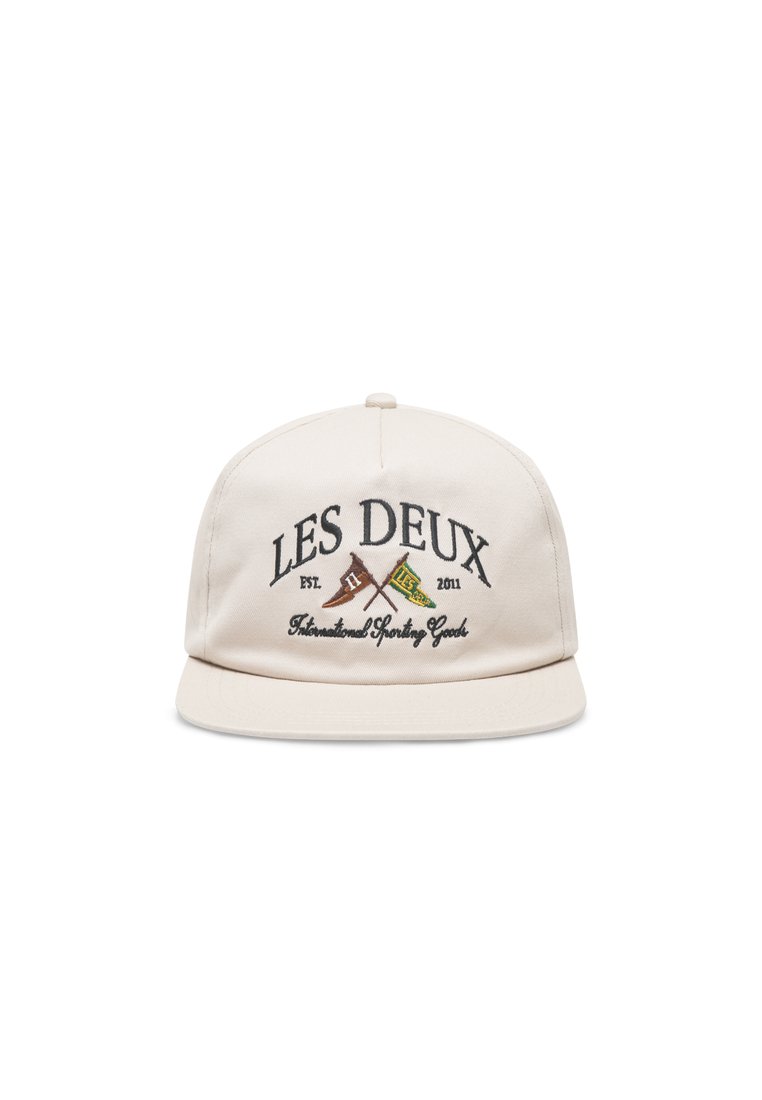 Beige caps med flat skygge, med broderte "LES DEUX"-tekst og krysset flagg i brun og grønn. Laget av stoff med en glatt tekstur.