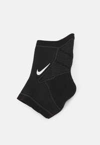 Fekete sportzokni, textúrált felülettel, kontrasztos fehér Nike logóval. Teljesítményre és támogatásra tervezve.