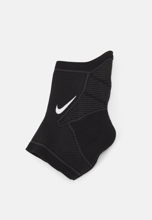 Black athletic sock with a textured surface, featuring a contrasting white Nike swoosh logo. Constructed for performance and support.