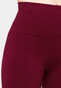 Bordeaux hoge taille legging met een gladde, rekbare textuur; heeft een geribbelde tailleband voor extra ondersteuning en comfort.