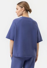 Paarse katoenen blend t-shirt met korte mouwen, raglan ontwerp en geribde ronde hals. Glad textuur en een losse pasvorm.