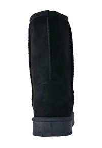 Zwarte suède enkelboot met een gestructureerde afwerking, platte rubberen zool en stiksels langs de zijkanten. Strak, minimalistisch ontwerp.