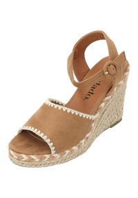 Tan suède wedge sandaal met een geweven jute hak. Voorzien van een enkelbandje met een ronde gesp en golvende stiksels op de voorband.