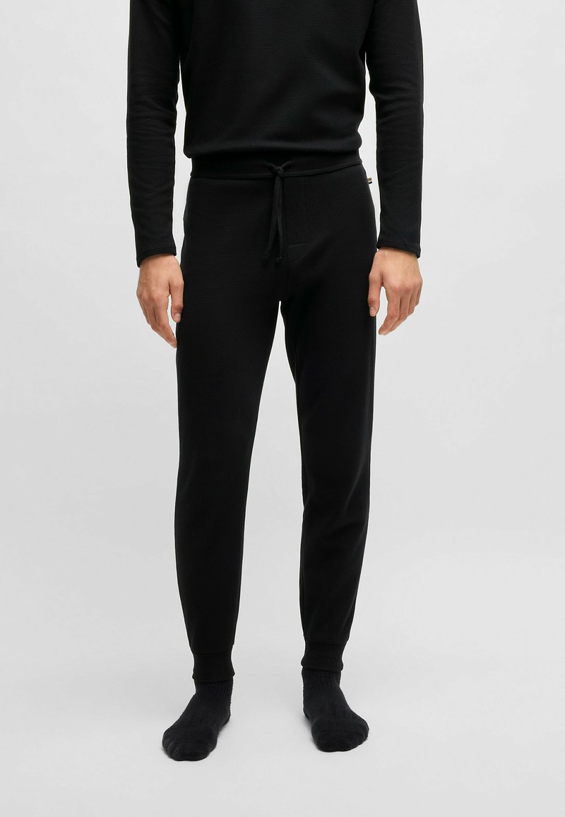 Svart langermet topp og matchende tapered joggebukser. Tøyet har et teksturert mønster. Bukser med snor i midjen og mansjetter.