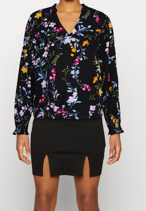 Black blouse with colorful floral print paired with black skirt featuring two front slits.