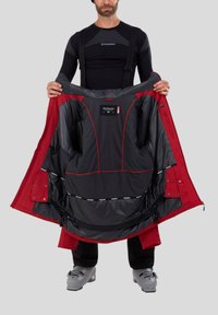 Rote Skijacke mit schwarzem strukturiertem Innenfutter, roten Akzenten, Reißverschlusstaschen und verstellbaren Trageriemen. Offen präsentiert, um das Innenfutter zu zeigen.