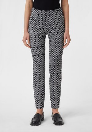 Schwarz-weiße gemusterte Hosen mit slim fit, die ein geometrisches Design aufweisen und aus einem glatten, leichten Stoff gefertigt sind.