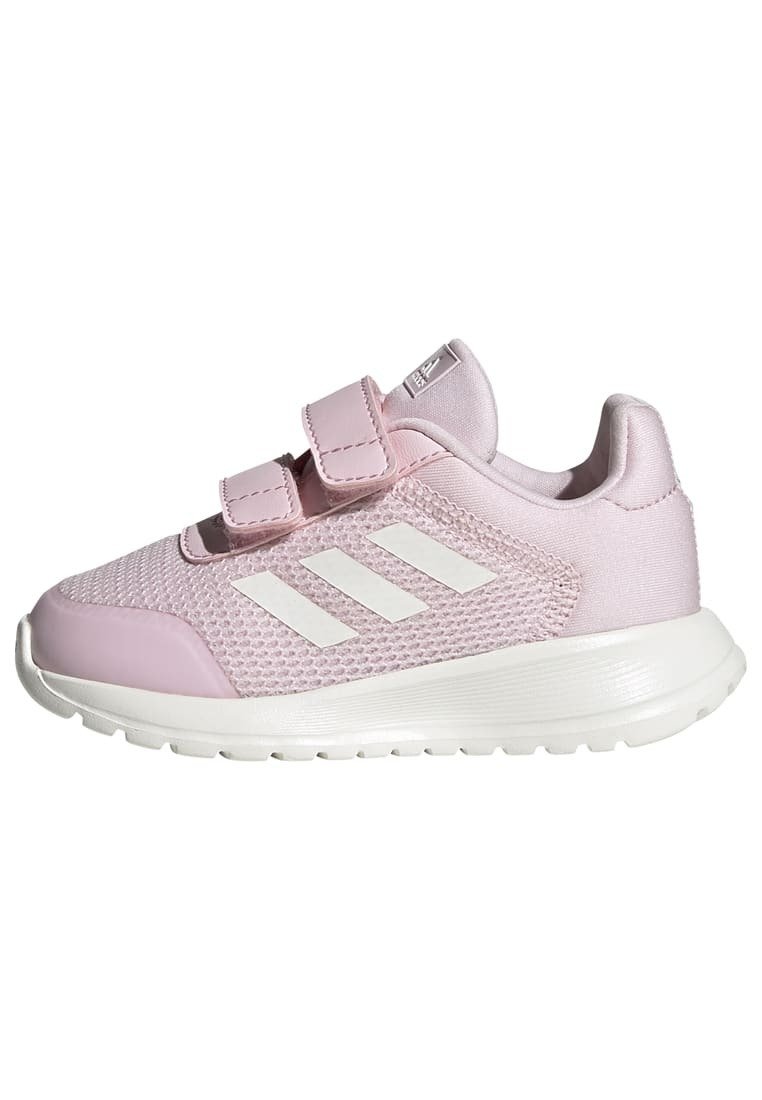 Zapatilla deportiva rosa con parte superior de malla transpirable y suela de goma. Cuenta con dos tiras de Velcro y tres franjas blancas en el lado.