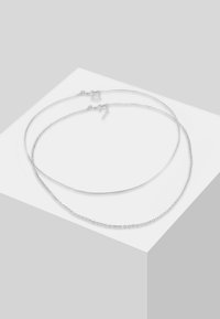 Due collane d'argento sovrapposte, una con catena metallica liscia e l'altra con catena a maglie. Entrambe presentano fermagli regolabili per la lunghezza.