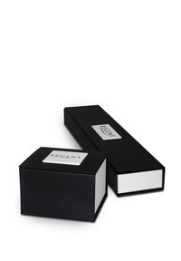 Deux boîtes en carton noir, l'une rectangulaire et l'autre carrée, avec des intérieurs blancs et une plaque logo argentée étiquetée "REGENT" sur le dessus.