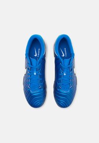 Blue soccer shoes with textured synthetic upper, white accents, and black sole. Features rounded toe and lacing system for secure fit.