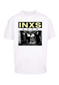 Hvid bomulds t-shirt med et sort-hvidt grafisk tryk af fire personer med teksten "INXS" i gult og "NEED YOU TONIGHT" nederst.