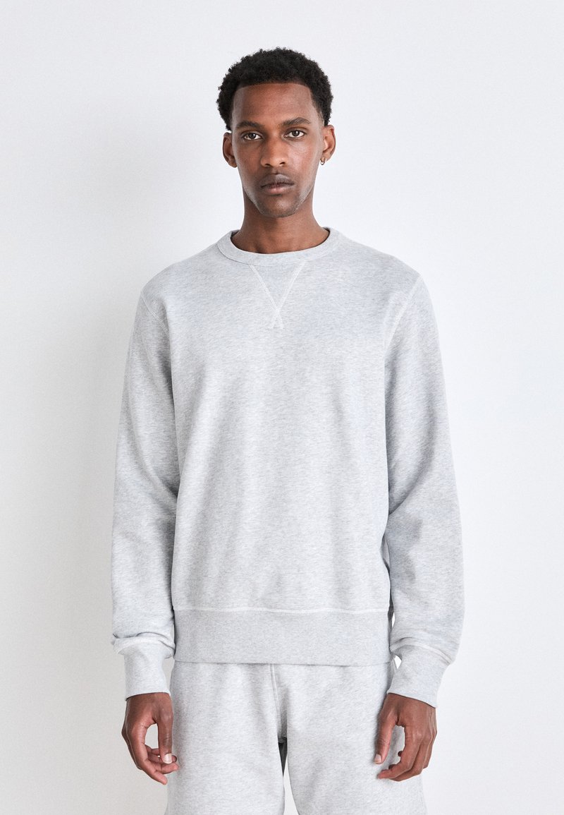 Gray sweatshirt made of soft fabric, featuring a round neckline, long sleeves, and ribbed cuffs and hem. Simple design with no patterns.