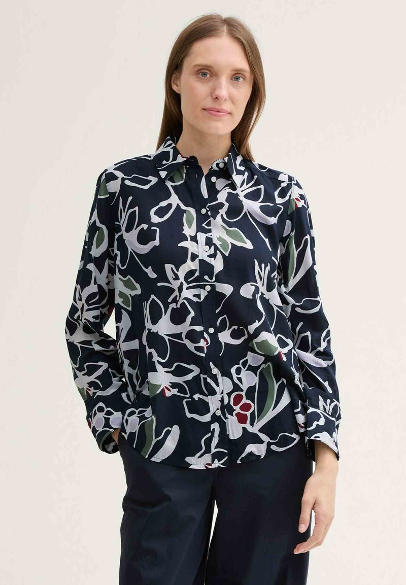 Navy button-up shirt with white, green, and red abstract floral pattern; made from a smooth fabric; long sleeves and collar.