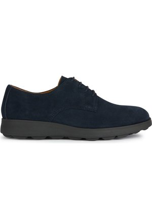 Zapatos de ante azul marino con punta redondeada, diseño minimalista de cordones y una suela de goma negra acolchada, que presenta sutiles acentos de costura.