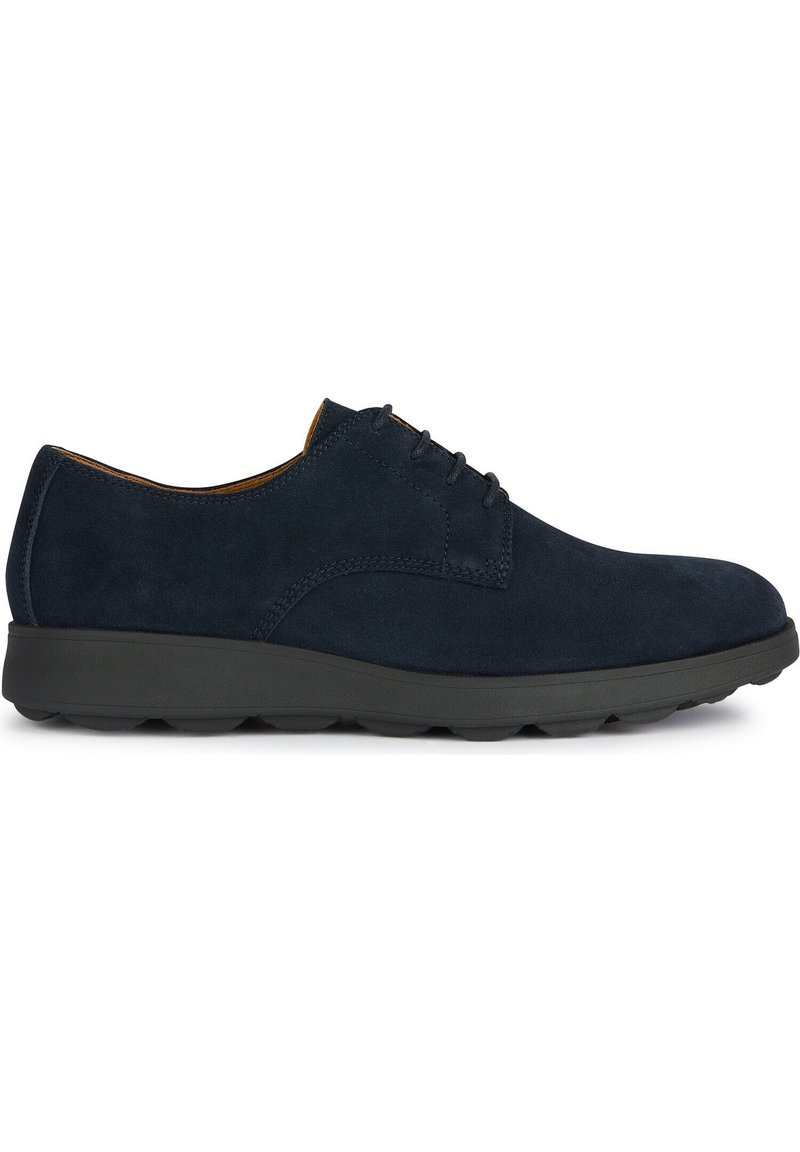 Chaussures en suede bleu marine avec un bout arrondi, un design minimaliste à lacets et une semelle en caoutchouc noir rembourrée, arborant des accents de couture subtils.
