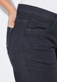 Donkerblauwe denim jeans met een gladde textuur, voorzien van een zijzak en een tailleband met een elastische inzet voor comfort.