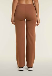 Pantaloni marroni a gamba larga realizzati in tessuto morbido e elastico, con una cintura elastica, progettati per il comfort e la facilità di movimento.