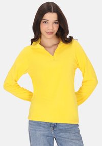 Gul langærmet pullover med en kvart lynlås krave, lavet af blødt materiale. Har manchetter ved ærmerne og en afslappet pasform.