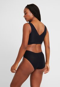 Black matching bralette and high-waisted briefs made from smooth, stretch fabric. Features a deep V-back design and wide straps.