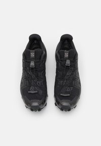 Zapatos deportivos negros con una parte superior texturizada, puntera reforzada y un diseño de cordones que incluye un sistema de ajuste tipo toggle para un ajuste seguro. Suela de tracción para un buen agarre.