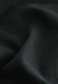 Tissu noir d'une texture douce et lisse avec un tissage fin et subtil, présentant un drapé naturel et sans motifs ni accents visibles.