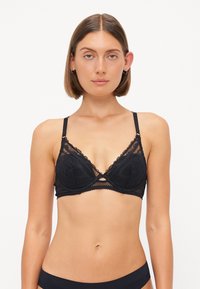 Zwarte kant bralette met een driehoekige vorm, gedetailleerde bloemenborduursel, verstelbare bandjes en een uitgesneden onderbust ontwerp.