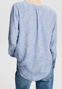 Blusa azzurro chiaro con un motivo a pois bianchi e azzurro chiaro, vestibilità rilassata, maniche lunghe e orlo arrotondato. Realizzata in tessuto morbido.