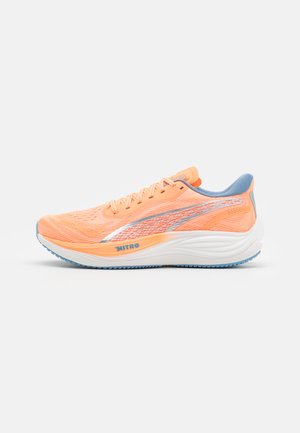 Orange running shoe with mesh upper, blue accents, and reflective stripes. Features a cushioned white sole and textured outsole for grip.