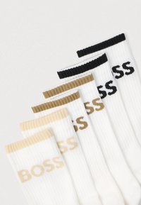 Set di sei calzini costinati bianchi, con risvolti di colori diversi: nero, verde oliva e beige, con il logo "BOSS" stampato in colori a contrasto.