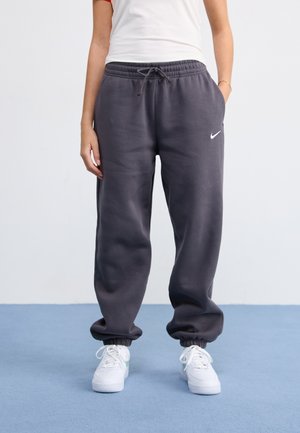 Pilkos sportinės kelnės, pagamintos iš minkštos medžiagos, su elastingu liemeniu ir raišteliu bei elastinėmis rankovėmis. Balta Nike logotipas kairiajame šlaunyje.