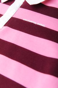 Polo majica s horizontalnimi bordo in roza črtami, belim ovratnikom in vezenjem "COLOURFUL REBEL" na prsih.