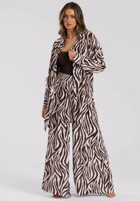 Conjunto de loungewear con estampado de cebra marrón y blanco que incluye una camisa larga con botones y pantalones de pierna ancha, fabricado en tejido ligero.