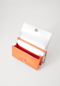 Oranžová kožená peněženka se stříbrným interiérem. Má zapínání na cvok, řetízkový popruh a přihrádku na karty. Hladký povrch po celém těle.