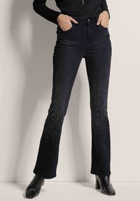 Zwarte flared jeans met een verloop van zilveren strass-steentjes op de onderbenen. Gemaakt van denim met een subtiele textuur en een hoog aangesloten taille.