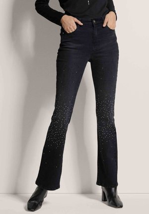 Black flared jeans featuring a gradient of silver rhinestones at the lower legs. Made of denim with a subtle texture, high-waisted design.