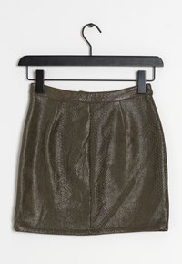 Jupe mini en imprimé serpent vert avec une surface texturée, dotée d'une taille plate et de plis pour plus de détail, suspendue à un cintre noir.