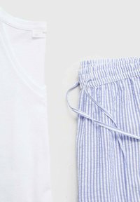 Canottiera bianca in cotone accanto a pantaloni a righe blu e bianche con cordoncino, realizzati in tessuto leggero. I pantaloni presentano una vestibilità comoda.