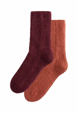 Ribbed socks in deep burgundy and rust orange, featuring a soft texture and a slightly metallic sheen. Both pairs have ankle-length design.