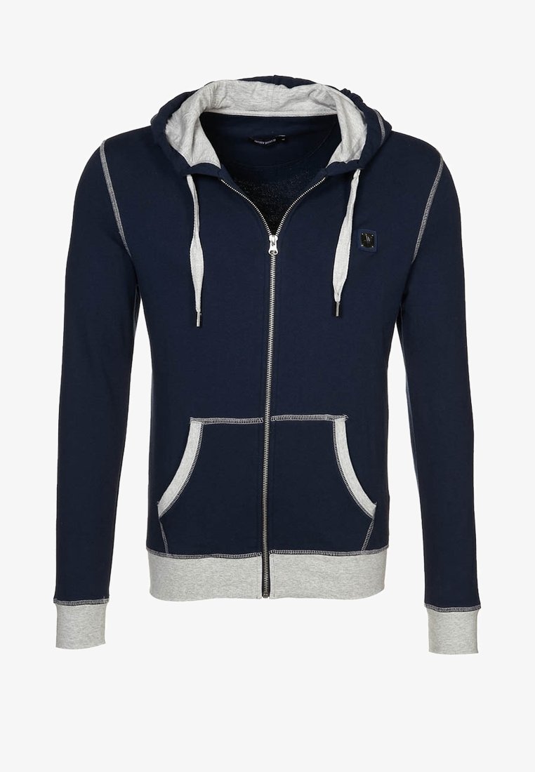 Marinblå zip-up hoodie med huva fodrad i grått, framfickor och kontrasterande sömmar. Tillverkad av mjukt tyg med en avslappnad passform.