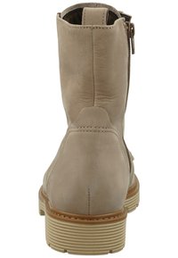Stivale alla caviglia in pelle beige con superficie texturizzata, punta arrotondata e zip laterale. Presenta una suola in gomma rigata per una buona aderenza.