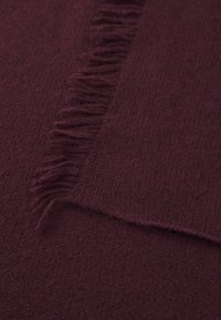 Burgundy tørklæde lavet af blødt, textured stof med frynset kanter, der viser en glat overflade og en rig, dyb farve.