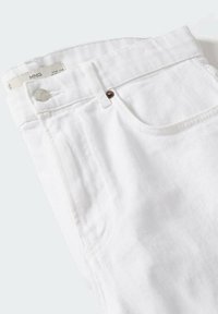 Jean en denim blanc plié, montrant une poche avant, une passants de ceinture, un bouton en métal et une étiquette de marque sur la ceinture.